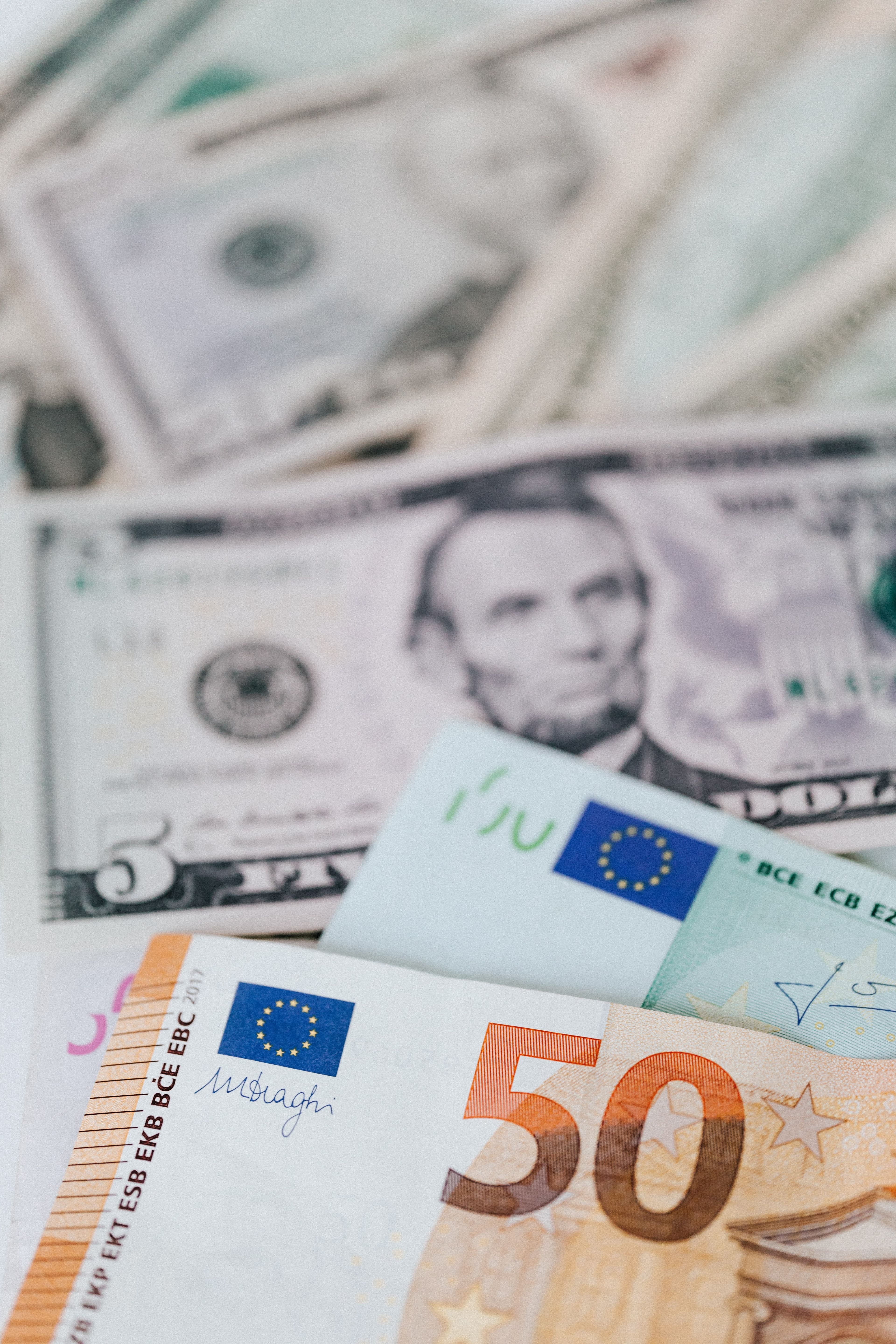 Banknoty euro i dolarów amerykańskich obok siebie, symbolizujące kilka walut trzymanych na jednym rachunku